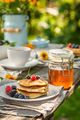 Fresh pancakes with fresh blueberries and honey in summer garden