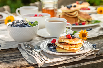 Closeup of pancakes with raspberries, blueberries and honey