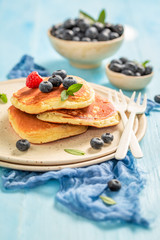 American pancakes with fresh blueberries and sugar on blue table