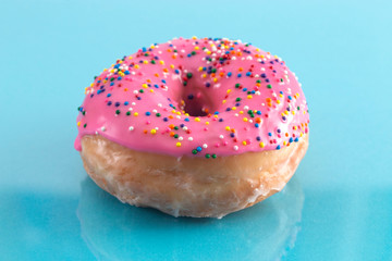 A Pink Sprinkle Donuts on a Turquoise Background