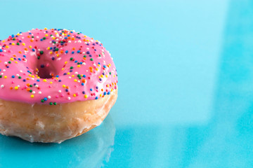 A Pink Sprinkle Donuts on a Turquoise Background