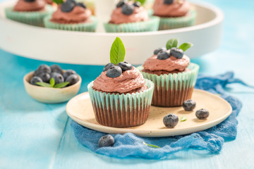 Muffins with chocolate cream and berries on blue table
