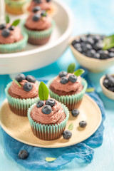 Tasty cupcake made of chocolate cream on blue table