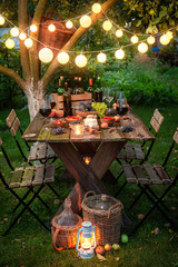 Preparation for supper with wine in illuminated summer garden