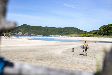 surfer walking with his dog at the beach