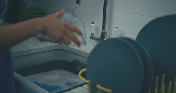 Woman cleaning dishes in the evening after dinner