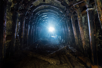 Dark abandoned coal mine with rusty lining in backlight