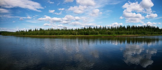 Reflection of blue shy with clouds in River, with forrest between river and sky