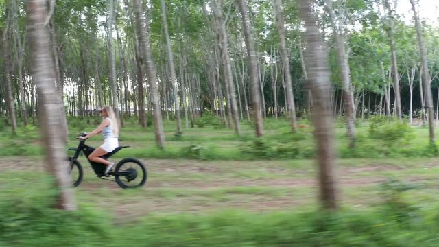 Drone view of woman on electric bicycle in the forest. Attractive woman riding her e-bike in the forest