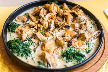 Mussels in a creamy spinach sauce in a pan.