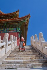 Caucasian brunette lady tourist climbing steps of traditional Chinese building