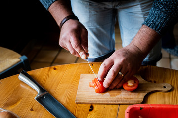 Mains d'un cuisinier en train de découper des tomates