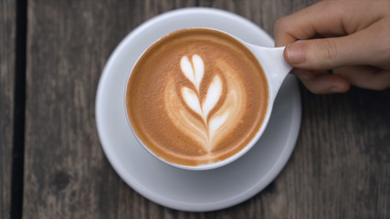 cup of coffee in hand on wooden background