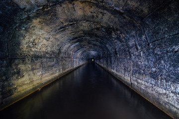 Dark flooded concrete vaulted drainage mine tunnel
