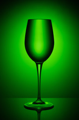 Wine glass with liquid on the background of green round gradient.
