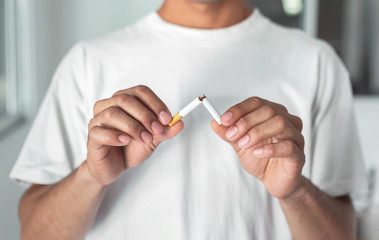 Stop smoking cigarettes concept. Portrait of beautiful  holding broken cigarette in hands. Happy ,...