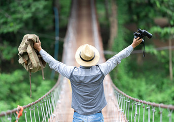 Happy celebrating winning success male tourist holding binoculars and backpack standing elated with...