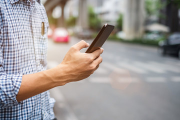Young man tourist or casual businessman ordering taxi via cab application on smartphone in city...