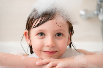 little girl in bath playing with foam