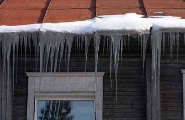 Icicles hang from the roof at the windows of the wooden house - Panorama HDR - High Dynamic Range