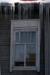 Icicles hang from the roof at the windows of the wooden house - Panorama HDR - High Dynamic Range