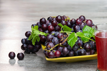 Grapes in a yellow dish, served with grape juice On an old wooden table