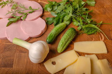 on the end cutting Board slicing of sausage and cheese with fresh cucumbers greens and a head of...