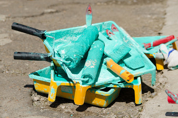 several paint rollers covered with green paint are in the tray
