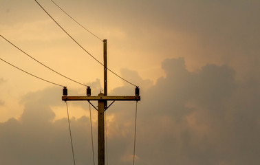Electric poles with cables of electric on sunset background in evening.