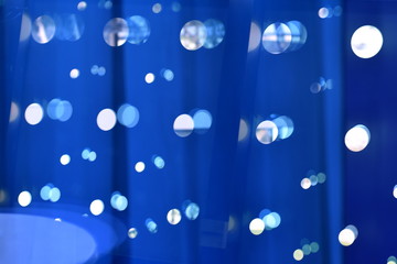 Abstract blue bokeh lights in rows on dark background. Glass reflection pattern.