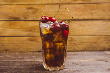 Refreshing cold cherry cola on the wooden background. Selective focus.