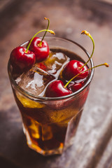 Refreshing cold cherry cola on the wooden background. Selective focus.