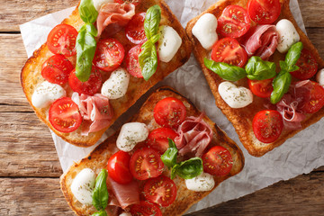Ciabatta sandwiches with mozzarella, tomatoes, ham and basil close-up. Horizontal top view
