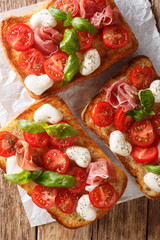 Ciabatta sandwiches with mozzarella, tomatoes, ham and basil close-up. Vertical top view
