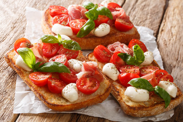 Italian open sandwiches with mozzarella, tomatoes, ham and basil closeup. horizontal