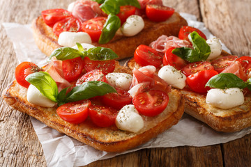 Ciabatta sandwiches with mozzarella, tomatoes, ham and basil close-up on the table. horizontal