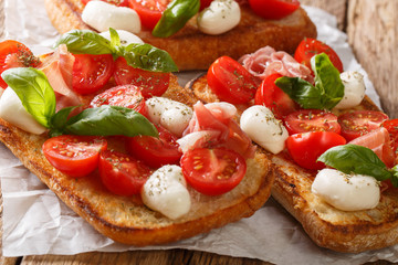 Delicious ciabatta with mozzarella, tomatoes, prosciutto and basil close-up on the table. horizontal