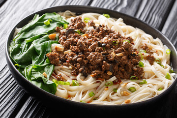 Traditional Chinese Sichuan Dan Dan Noodles with minced meat and greens in a plate. horizontal