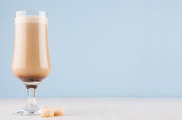 Fresh summer coffee drink in goblet with biscuits in light blue modern restaurant interior, copy space.