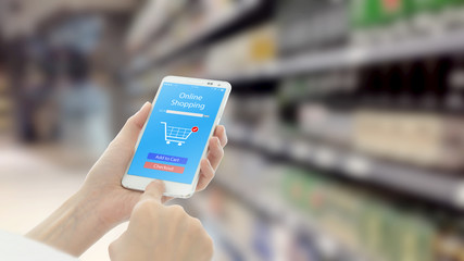 Woman using smart phon while shopping in supermarket