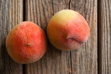 Fototapeta na wymiar two peach fruits on old weathered wooden table background