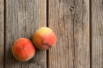 two peach fruits on old weathered wooden table background