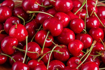 Sweet fresh organic cherry background close-up. Cherry in the plate with leaves on a dark background