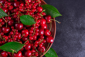 Sweet fresh organic cherry background close-up. Cherry in the plate with leaves on a dark background