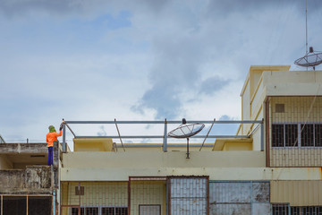 Fototapeta premium Worker welding the steel part for roof before it is going to rain.