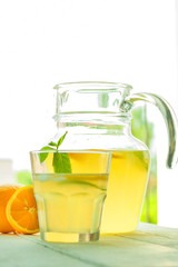 Jug and glass with lemonade on wooden table.