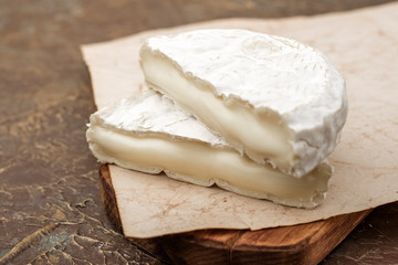 two pieces of tasty white mold cheese on a cutting board. Snack to wine. Copy space