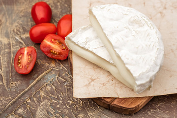 white mold cheese on a cutting board and tomatoes. brie cheese Copy space