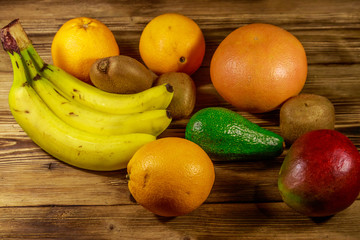 Assortment of tropical fruits on wooden table. Still life with bananas, mango, oranges, avocado, grapefruit and kiwi fruits