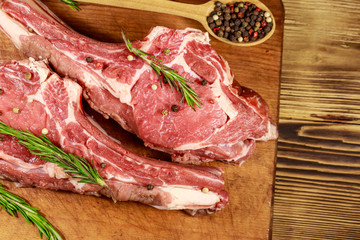 Raw fresh beef rib eye steaks on bone with spices and rosemary on wooden table. Top view